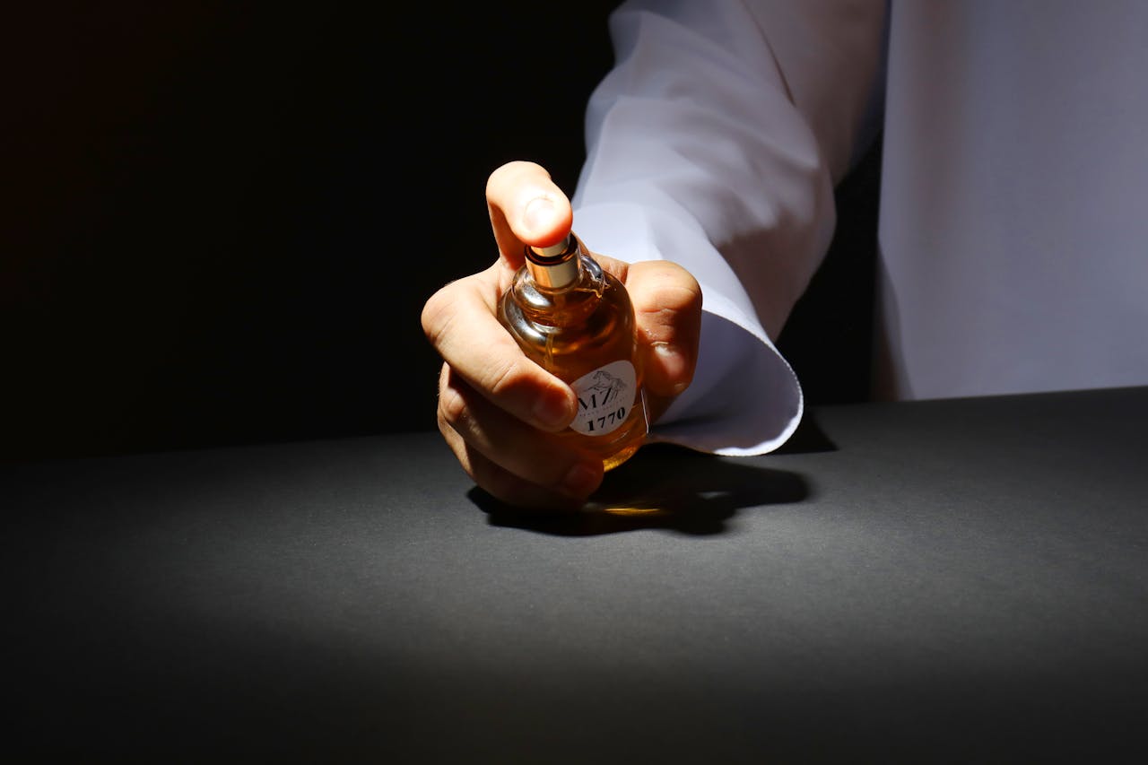 A hand elegantly holding a perfume bottle against a dark backdrop, highlighting luxury fragrance.